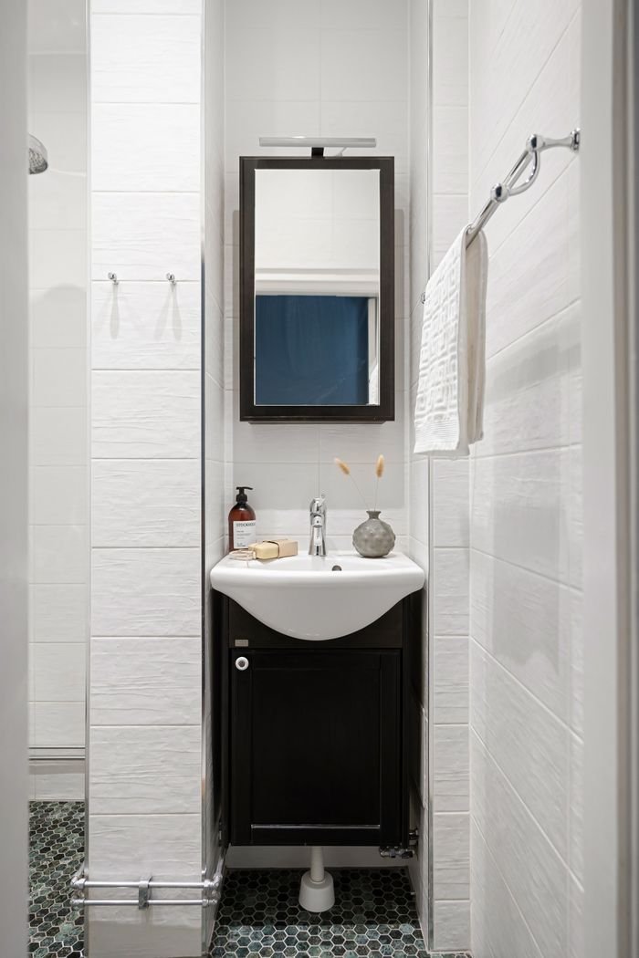 A sleek bathroom design featuring a mirror, sink, and towel set against white tiled walls.