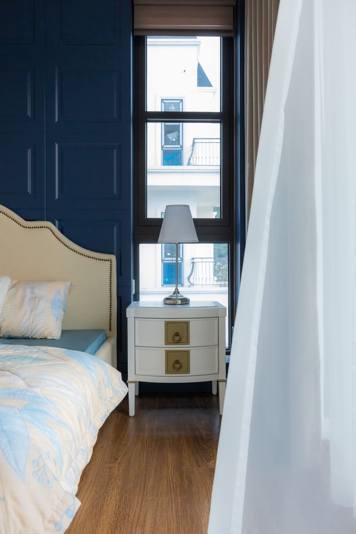Sophisticated bedroom design featuring a beige headboard, blue walls, and wood flooring with ample natural light.