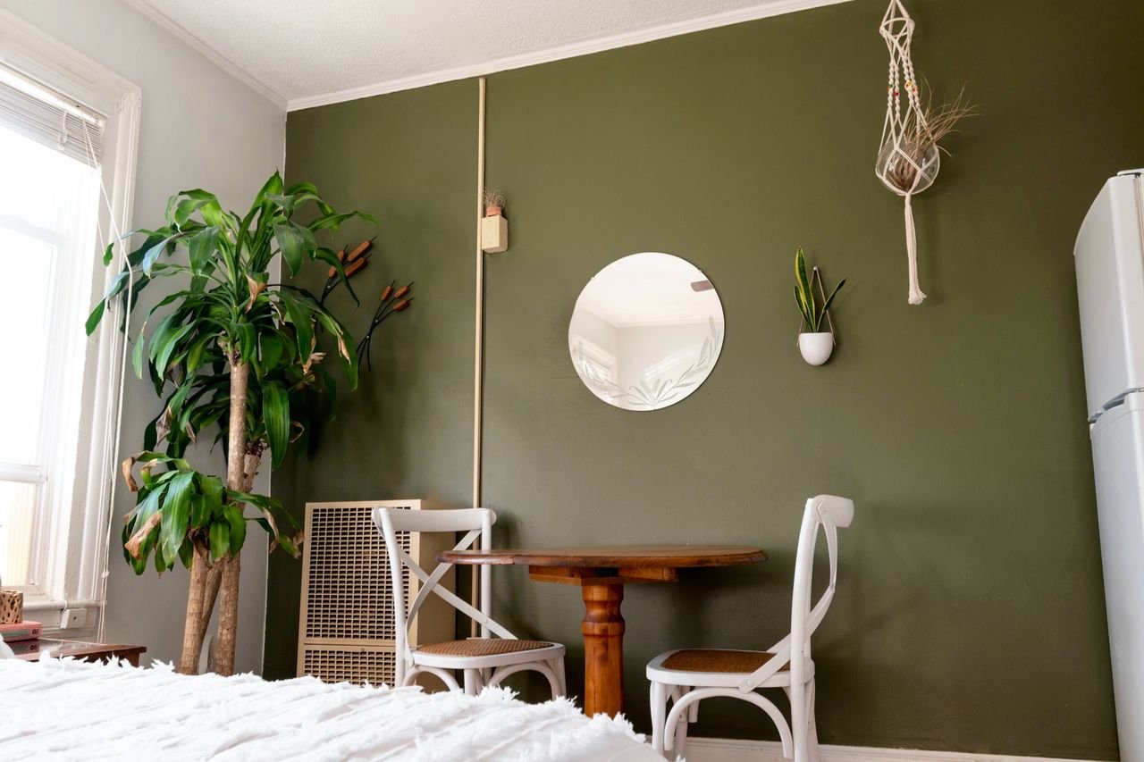 From below of modern room interior with bed and table near fridge and potted tree in flat